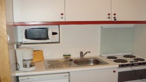 A compact kitchen with a microwave, a coffee maker, a sink, and a stove. - STUDIO No. 15, on the station (Gérardmer)
