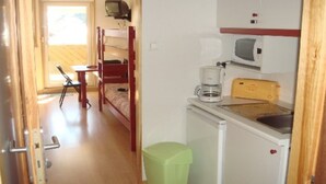 A compact room with a bunk bed, a small kitchenette, a single chair, and a trash bin. - STUDIO No. 15, on the station (Gérardmer)