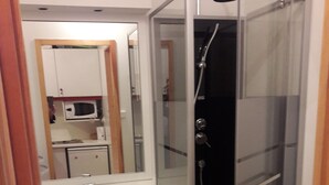 A bathroom with a glass-enclosed shower, a sink, and cabinets. - STUDIO No. 15, on the station (Gérardmer)