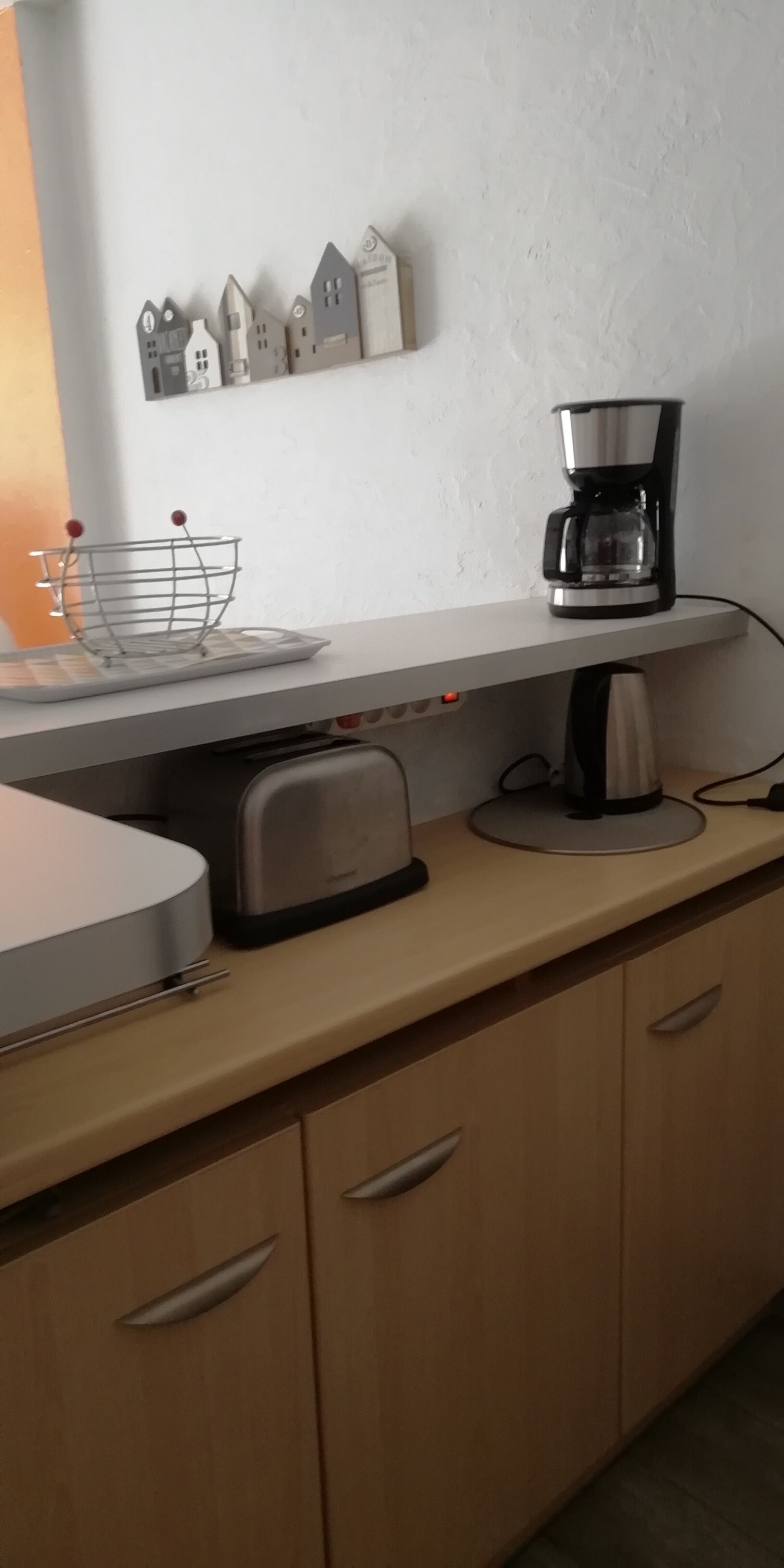 A kitchen with a coffee maker, toaster, and a metal rack with red balls.