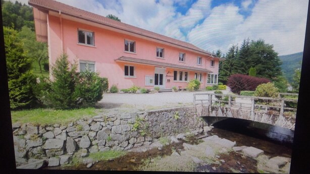 Un bâtiment rose avec un pont en pierre et de la verdure.