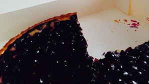 Une boîte à pizza posée sur une table, contenant une part de pizza à moitié mangée.