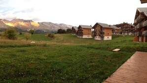 Une vue sur un paysage montagneux avec une terrasse en bois et des bâtiments de style chalet.