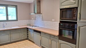 Una cocina con gabinetes grises, una ventana, un microondas y un horno.