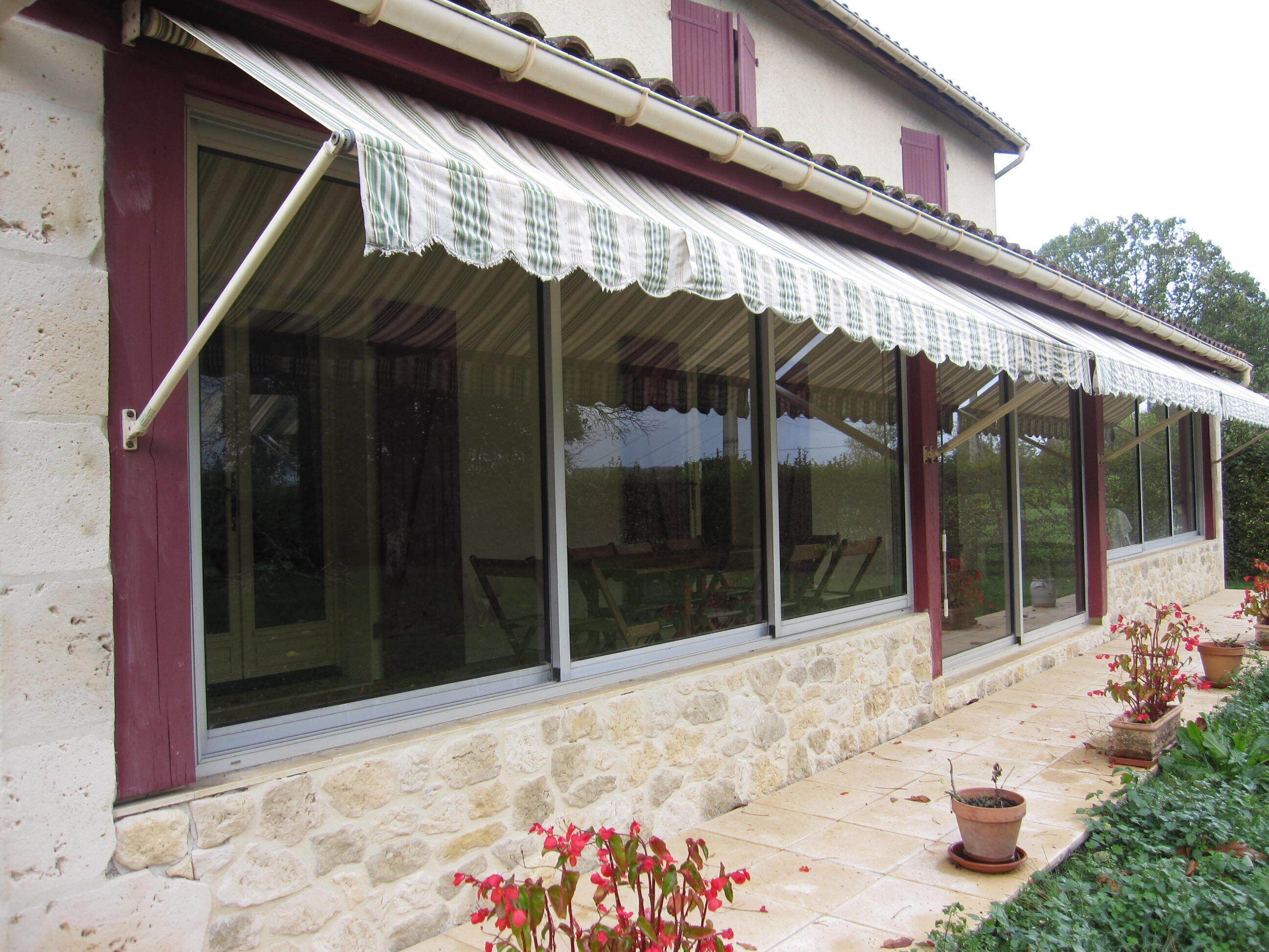 A stone building with large windows and a covered patio area.