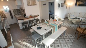 A spacious living area with a dining table set for four, a kitchen with a bar, and a cozy seating area with a sofa and chairs. - OLD: charming house 100m from the beach (2 bedrooms, 2 bathrooms) (Noirmoutier-En-L'île)