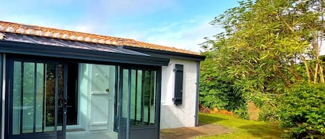 A modern house with a large sliding glass door entrance, a tiled roof, and a well-maintained garden.