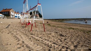 A beach with a swing set and a building in the background. - OLD: charming house 100m from the beach (2 bedrooms, 2 bathrooms) (Noirmoutier-En-L'île)