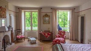 A room with a fireplace, two windows, a mirror, and a bed. - Family home in a wooded park with swimming pool near Futuroscope (Thurageau)