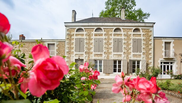A stone building with arched windows and shutters, surrounded by a garden with pink roses. - Family home in a wooded park with swimming pool near Futuroscope (Thurageau)