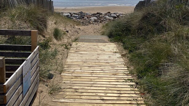 Ein hölzerner Weg führt zu einem Strand mit freiem Blick auf den Ozean.
