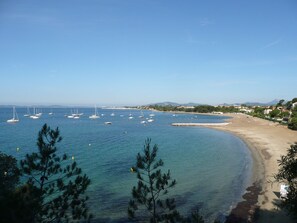 A coastal view with a sandy beach, clear blue water, and several sailboats. - Charming villa close to the beach with 3 air-conditioned bedrooms. (La Londe-Les-Maures)