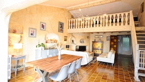 A spacious living area with a wooden dining table, white sofas, and a balcony with a railing.