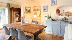 A dining area with a wooden table, modern chairs, a bookshelf, decorative wall art, and a cabinet with natural elements.