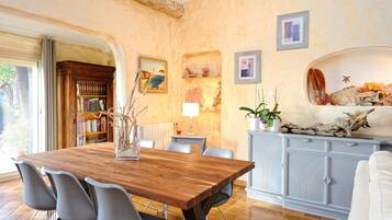 Un espace repas comprenant une table en bois, des chaises modernes, une bibliothèque, des œuvres d’art décoratives au mur et un meuble agrémenté d’éléments naturels.