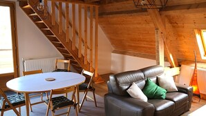 Une pièce chaleureuse de style loft, avec un escalier en bois, un canapé en cuir, une table ronde et un radiateur.