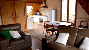 Un salon chaleureux avec des canapés en cuir, une table à manger et une cuisine en arrière-plan.