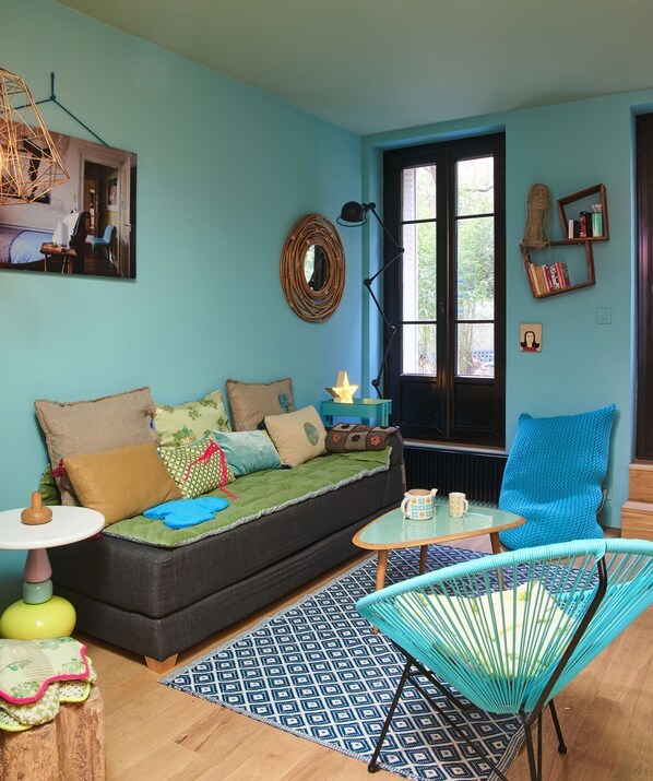 A cozy living room with a sofa, a small table, a chair, and a patterned rug.