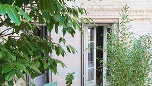 A small outdoor seating area with a table and chairs, surrounded by potted plants and a large tree. - atypical design studio, 2 terraces (Paris)