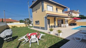 A two-story house with a swimming pool, outdoor seating, and a covered barbecue area. - holiday house with pool in azeitao (azeitao)