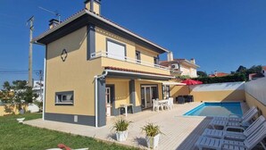 A two-story house with a swimming pool, outdoor seating, and a covered patio area. - holiday house with pool in azeitao (azeitao)