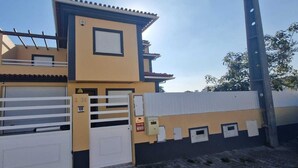 A two-story building with a yellow facade, white garage doors, and a metal fence. - holiday house with pool in azeitao (azeitao)