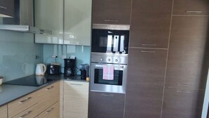 A modern kitchen with a built-in oven, a microwave, and a coffee maker. - holiday house with pool in azeitao (azeitao)