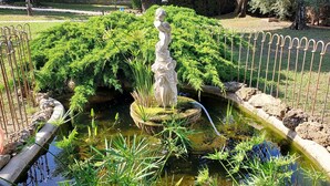 A pond with a statue, surrounded by a metal fence and lush greenery. - Beautiful Provencal Stone Villa with Large Pool and Pool House (Grasse)