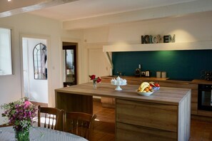 A modern kitchen with wooden countertops, a central island with a fruit bowl, and a 'Kitchen' sign above the backsplash. - Charming 17th century residence, Calm, Livradois Forez Natural Park, Olliergues (Olliergues)