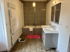 A bathroom with a white bathtub, a white sink, a scale, and a red bath mat. - Charming 17th century residence, Calm, Livradois Forez Natural Park, Olliergues (Olliergues)