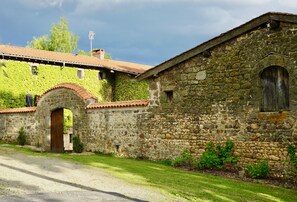 A stone building with an arched entrance, ivy-covered walls, and a red-tiled roof. - Charming 17th century residence, Calm, Livradois Forez Natural Park, Olliergues (Olliergues)