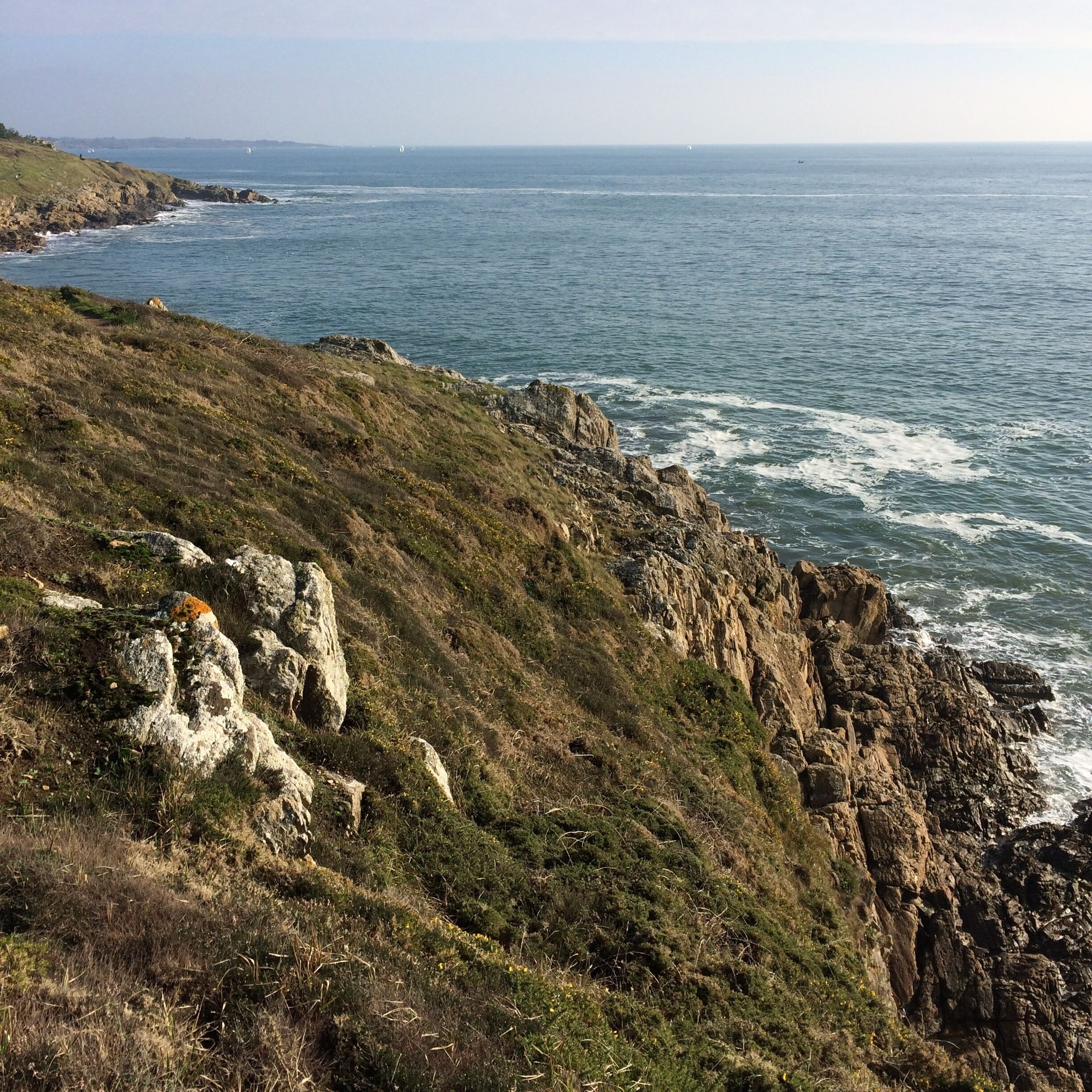 A coastal landscape with rocky cliffs and the sea.