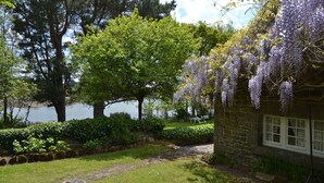 A stone building with a garden path leading to a bench. - New - Charming thatched cottage in the water with swimming pool  (Pointe de Grignallou)