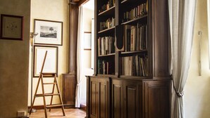 A room with a wooden bookshelf, a ladder, and a tiled floor. - Charming apartment in the historic center (Roma)