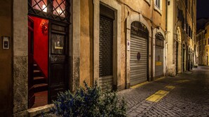 A narrow cobblestone street with closed shop fronts and a red door leading to a staircase. - Charming apartment in the historic center (Roma)