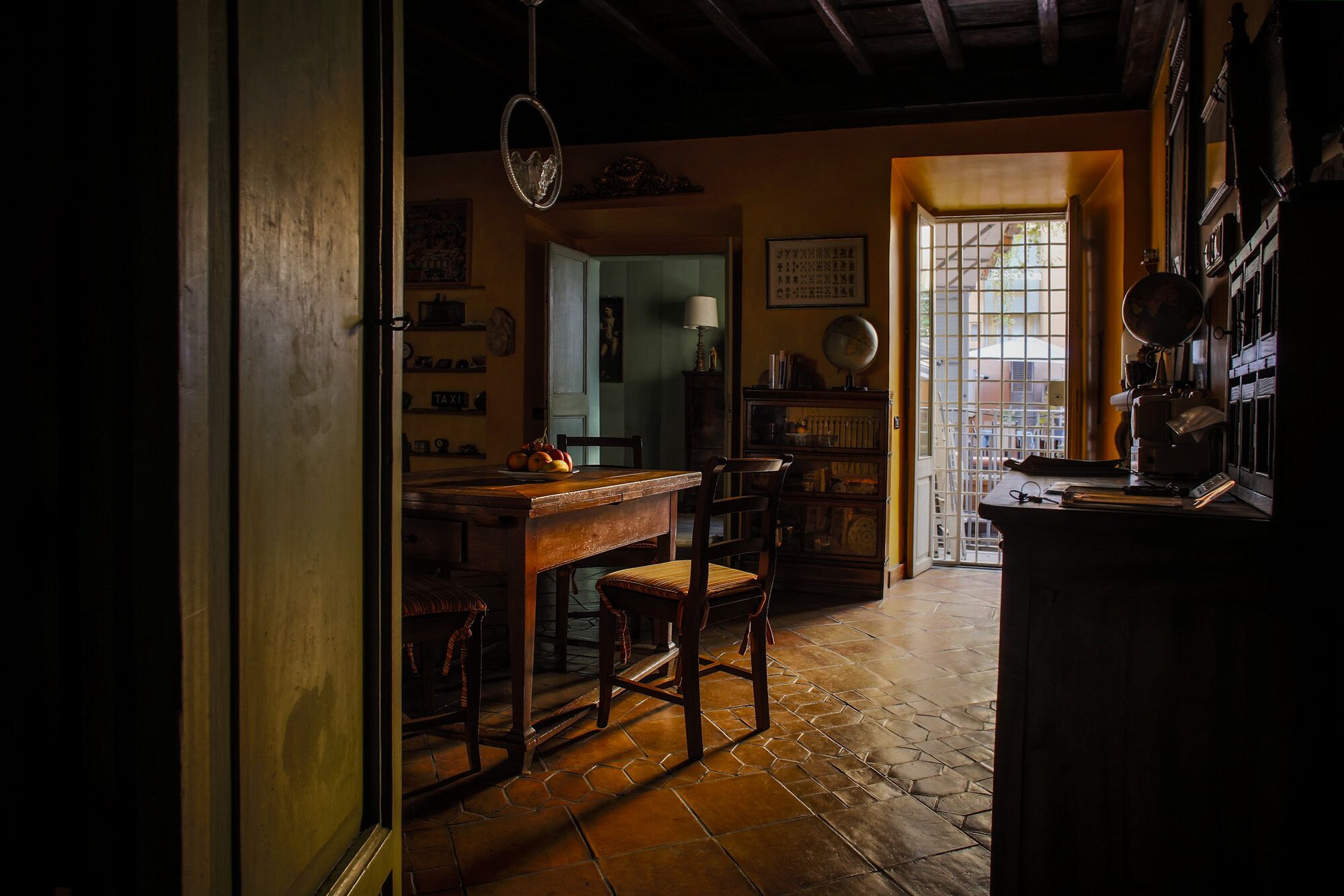 Une pièce faiblement éclairée, avec une table en bois, des chaises et un globe terrestre posé sur une étagère.