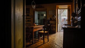 A dimly lit room with a wooden table, chairs, and a globe on a shelf. - Charming apartment in the historic center (Roma)