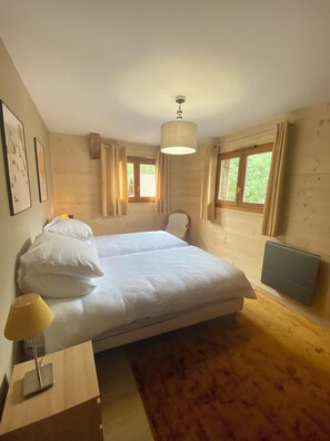 A bedroom with a bed, a bedside table with a lamp, a window with curtains, and a ceiling light. - Very spacious apartment for 8 people (Les Contamines-Montjoie)