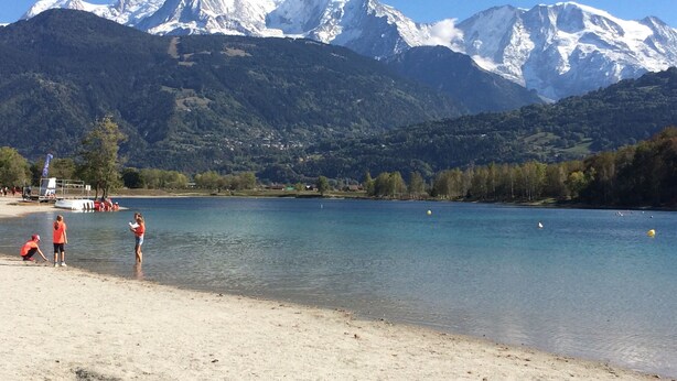 Un lac avec des montagnes en arrière-plan et des personnes sur la rive.