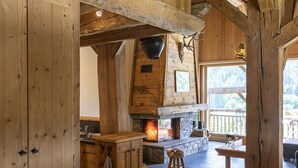 A rustic wooden interior with a stone fireplace, wooden beams, and a clock on the wall. - Pags Haut, Pags Haut (Châtel)