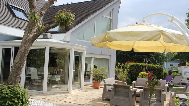 A patio with outdoor furniture, a covered seating area, and a potted plant.