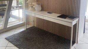 A modern room with a white desk, a grey rug, and a wooden slat wall.