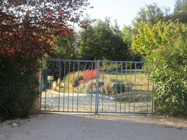 A gated area with a gravel path leading to a fenced entrance. - Detached villa in the heart of a winegrowing estate, a stone's throw from Mont Ventoux. (Visan)