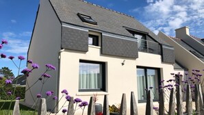 Een modern huis met twee verdiepingen, een schuin dak, grote ramen en een zichtbare schoorsteen.