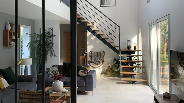Un vaste espace de vie agrémenté d’un escalier moderne, d’une grande fenêtre et d’une vue sur l’extérieur.