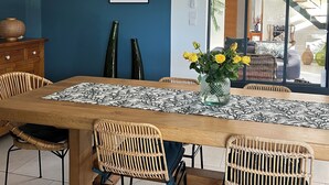 Un coin repas avec une table en bois, des chaises en osier et un vase rempli de fleurs jaunes.