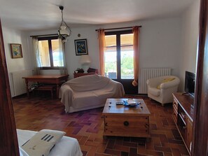 Ein Zimmer mit einem Bett, einem Schlafsofa, einem Holztisch, einem Fernseher und einem Fenster mit Vorhängen.
