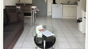 A living room with a sofa, a glass coffee table, and a staircase leading to an upper level.