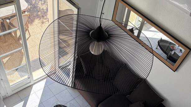 A modern living room with a large window, a black pendant light, a sofa, and a coffee table.