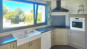 A kitchen with a built-in dishwasher, a window with a view of greenery, and a ceiling with a skylight. - Charming new house with garden to the South of Wimereux and close to t (Wimereux)